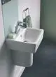 Handwaschbecken von Ideal Standard, schwenkbarer Handtuchring aus Chrom, Seife auf Ablage und grünes Handtuch. Minimalistisches Design in modernem Badezimmer.